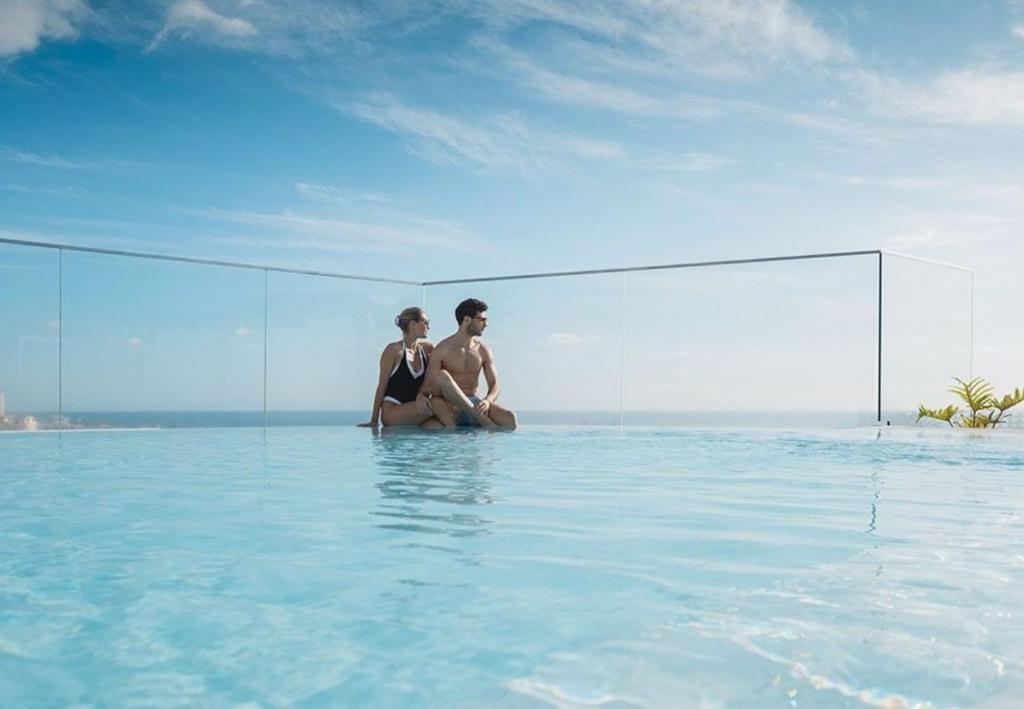 Couple relaxing in the rooftop infinity pool overlooking the Atlantic ocean in Tenerife